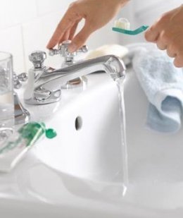 Woman running water and holding a toothbrush